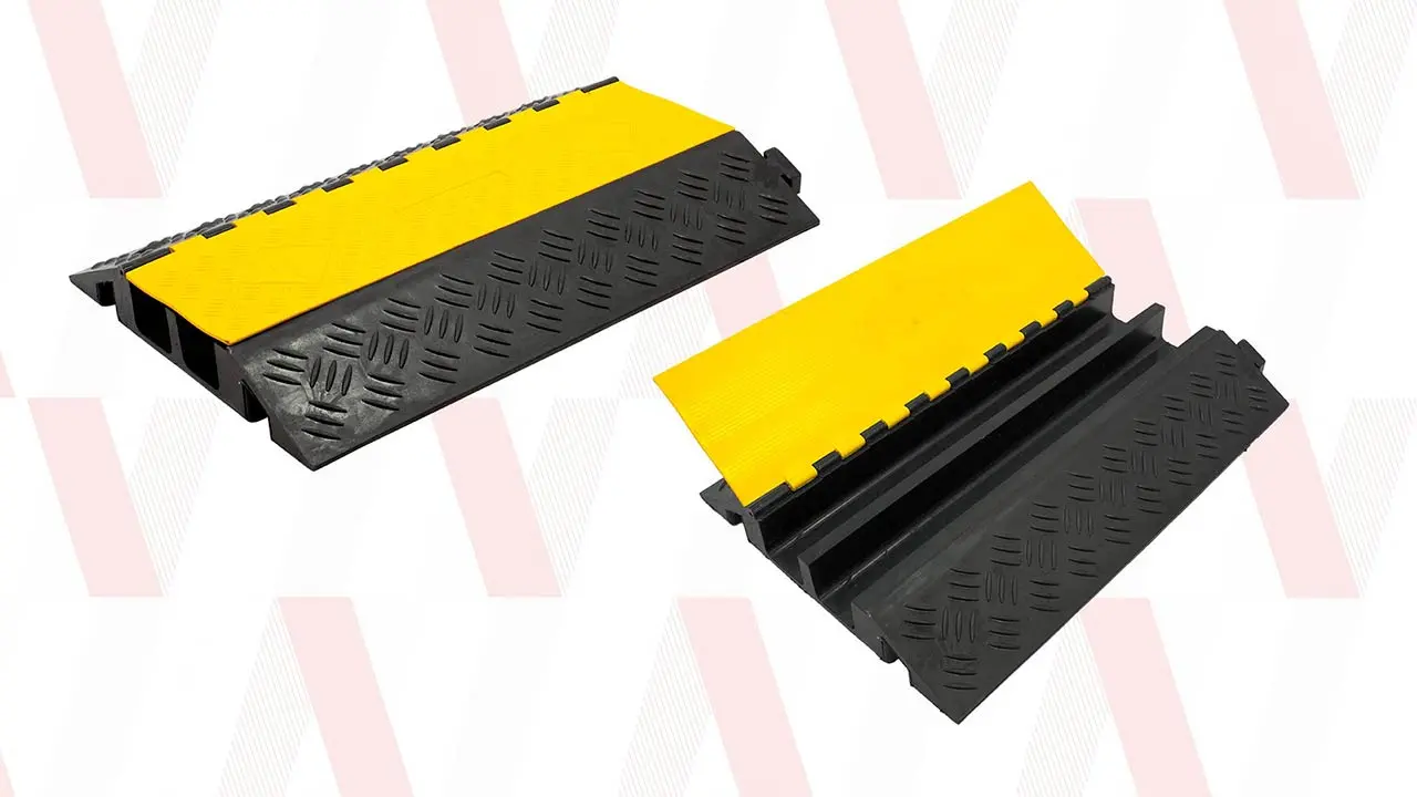Pasacables de suelo amarillo y negro de 5 canales protegiendo el cableado el&eacute;ctrico en una nave industrial con tr&aacute;fico de carretillas.