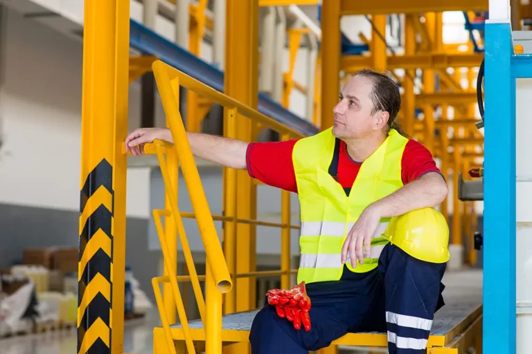 T&eacute;cnico de mantenimiento evaluando un protector de esquina amarillo y negro instalado en una columna de hormig&oacute;n de un aparcamiento.
