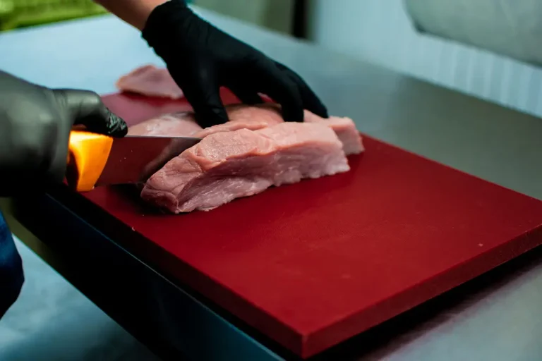Carnicero profesional troceando carne sobre una tabla de corte industrial de polietileno P500 blanco.