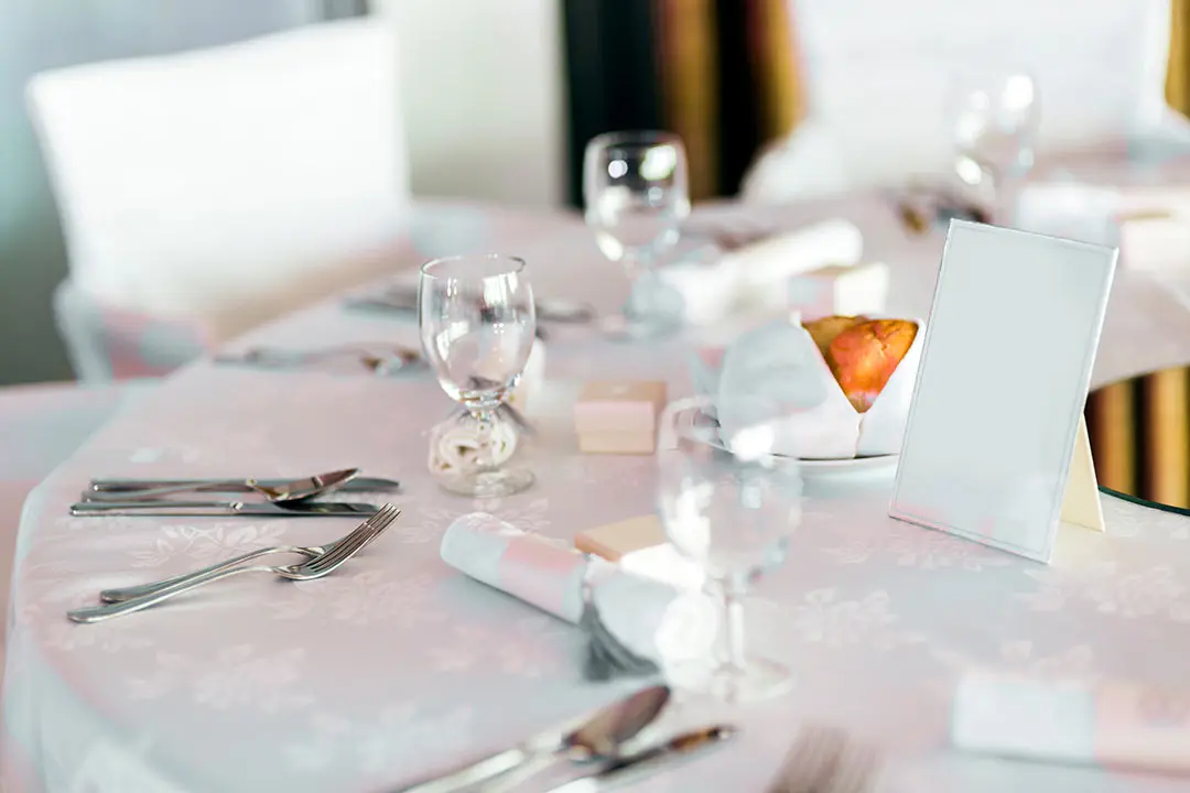 Portacartas de sobremesa de metacrilato transparente exhibiendo un men&uacute; de postres y c&oacute;cteles en la mesa de un restaurante elegante.