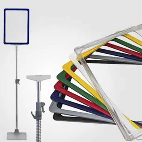 Sistema integral de carteler&iacute;a modular para supermercados, mostrando marcos de pl&aacute;stico ABS de colores con fundas protectoras, montados sobre tubos telesc&oacute;picos y bases de suelo.